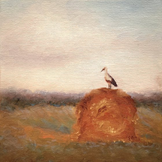 Stork on a haystack, in frame