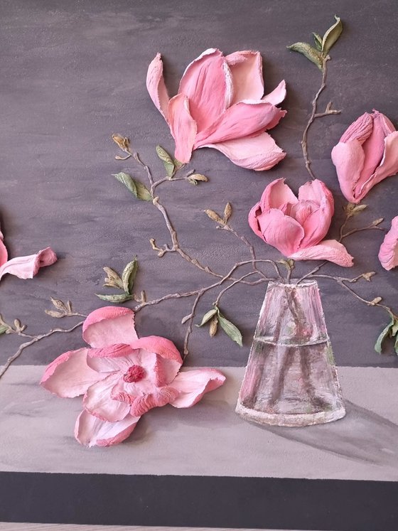 Pink Magnolia on a gray background. Relief still life with a branch of large flowers in a glass vase. Spring blooming