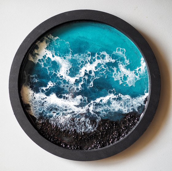 Round window overlooking the sea in a black frame