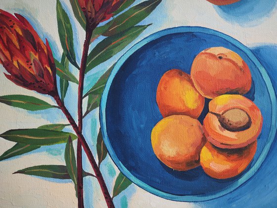 Protea flowers and apricots on blue plate