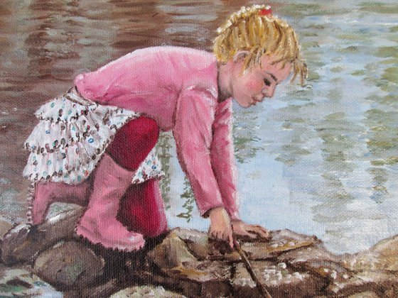 Girl in pink boots playing by a lake