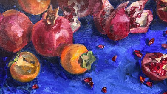 Pomegranates and persimmons on blue