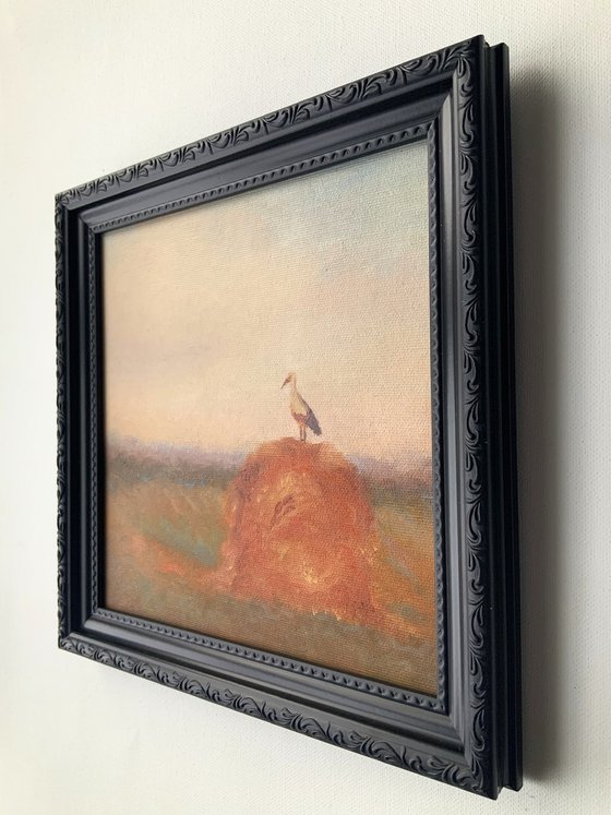 Stork on a haystack, in frame